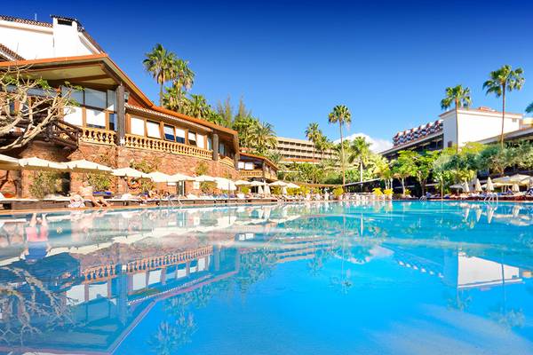 Ein großer Swimmingpool im Parque Tropical Hotel mit Loungeliegen und Sonnenschirmen.