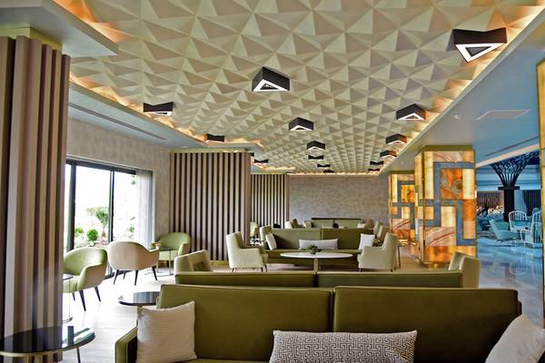 Das elegante Interieur des Royal Wings Hotel-Lobbys mit grünen Sofas, hellen Wänden und geometrischen Mustern.