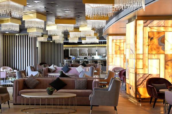 Lobby des Royal Wings Hotels mit eleganten Möbeln, hängenden Kronleuchtern und einer Theke.