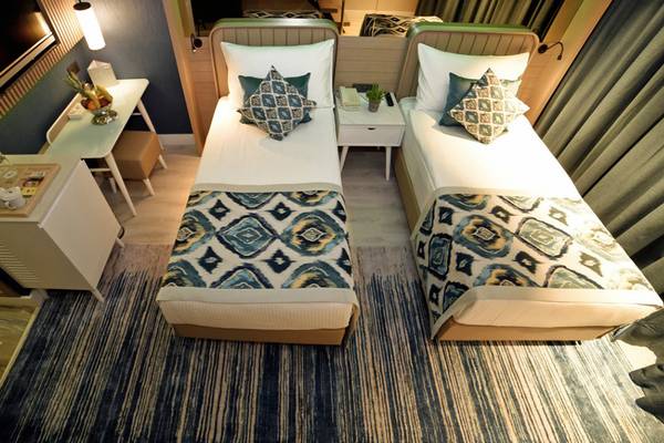 Doppelbett-Zimmer im Royal Wings Hotel mit zwei bequemen Betten, Dekor und Möbeln.