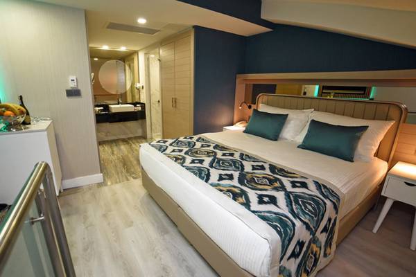 Schlafzimmer im Royal Wings Hotel mit Doppelbett, Nachttisch, Fernseher und Balkonzugang.
