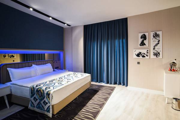 Das elegante Hotelzimmer im Royal Wings Hotel mit einem Bett, blauen Vorhängen und Dekor.