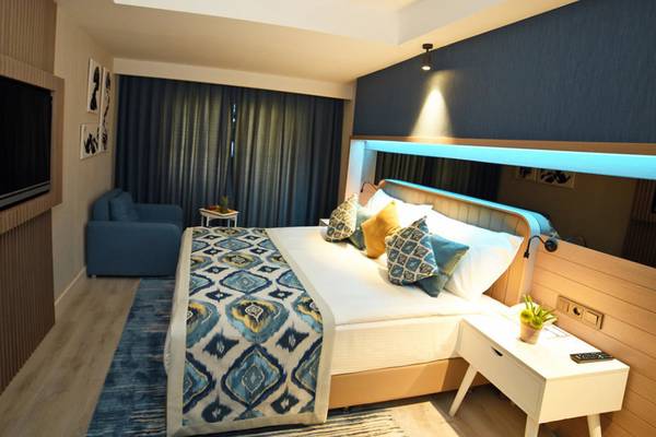 Innenansicht eines Hotelzimmers mit Doppelbett, Fernseher und Beistelltisch.
