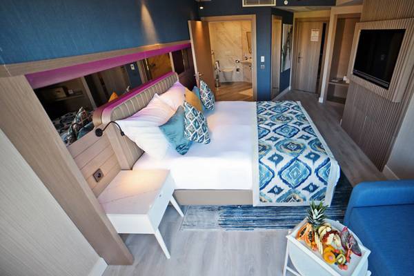 Innenansicht der Suite im Royal Wings Hotel mit Bett, Couch, Nachttischen und Fernseher.