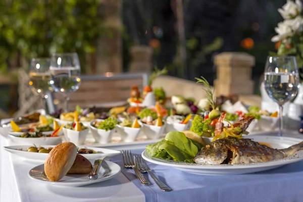 Gedeckter Tisch im Freien im Royal Wings Hotel mit Fisch, Salaten und Getränken.