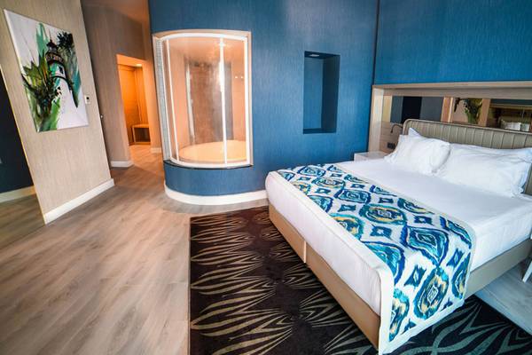 Ein Schlafzimmer im Royal Wings Hotel mit einem großen Bett, blauen Wänden und einer separaten Dusche.