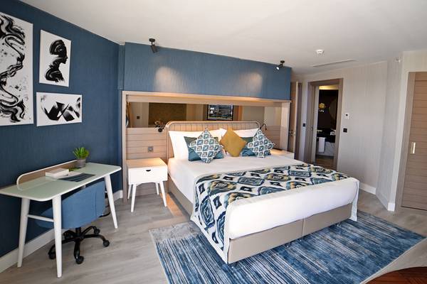 Schlafzimmer im Royal Wings Hotel mit Doppelbett, Schreibtisch und blauem Teppich.