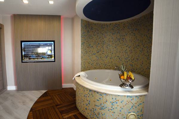 Ein Badezimmer im Royal Wings Hotel mit einem Whirlpool, Fernseher und Dekor.