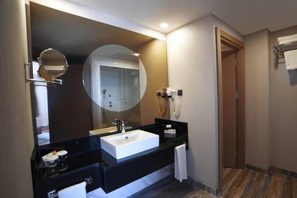 Badezimmer im Royal Wings Hotel mit Spiegel, Waschbecken und Toilettentür.