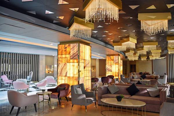 Lobby des Royal Wings Hotels mit eleganten Möbeln, Kronleuchtern und einer großen Marmorsäule.