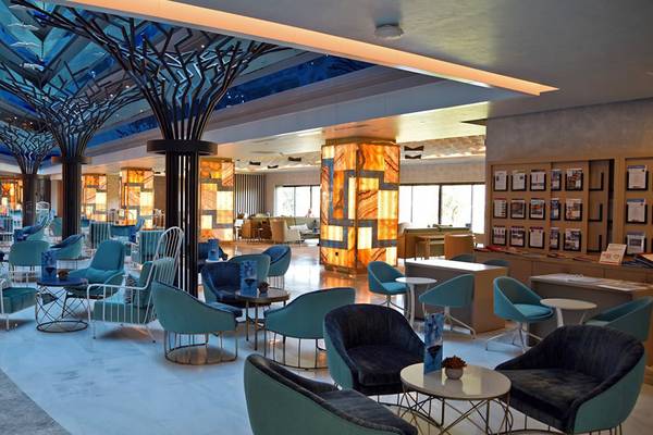 Lobby des Royal Wings Hotels mit blauen Möbeln und hohen Decken.