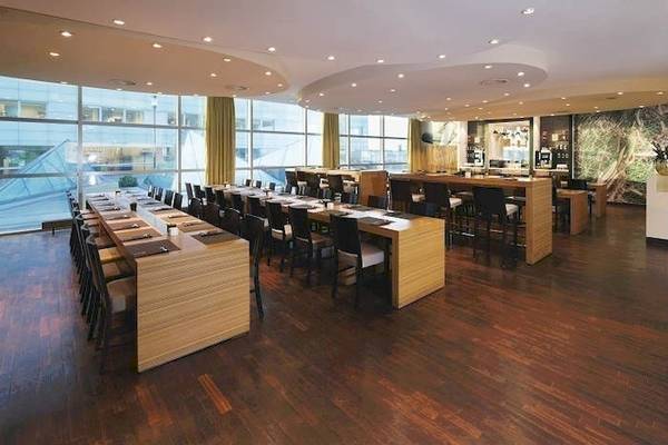 Innenansicht des Konferenzraums im Mövenpick Amsterdam City Centre mit langen Tischen und Stühlen.