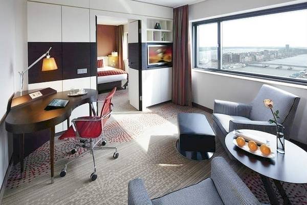 Hotelzimmer im Mövenpick Amsterdam City Centre mit Schreibtisch, Stuhl und Blick auf die Stadt.