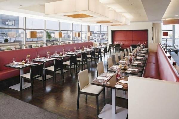 Restaurant im Mövenpick Amsterdam City Centre mit gedeckten Tischen und roter Bestuhlung.