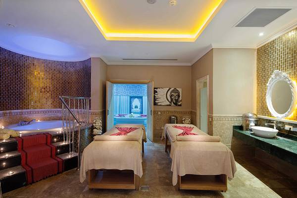 Innenansicht des Massageraums im Crystal Sunset Luxury Resort & Spa mit zwei Massagetischen und einem Whirlpool.