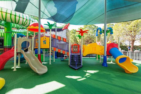Kinderspielplatz im Freien unter einem blauen Baldachin mit Rutschen und Klettergerüsten