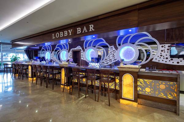 Lobby Bar im Crystal Sunset Luxury Resort & Spa mit blauen Beleuchtungselementen und geschwungenen Dekor.