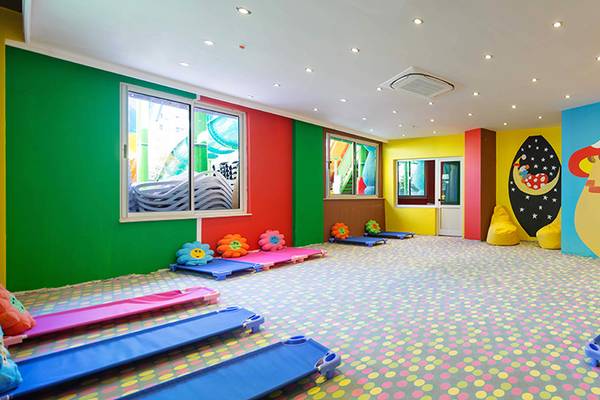 Kinderzimmer im Crystal Sunset Luxury Resort & Spa mit bunten Wänden, runden Möbeln und einem großen Wandbild.