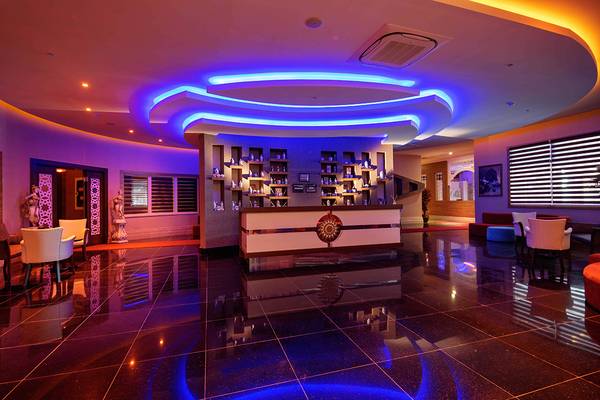 Empfangsbereich des Crystal Sunset Luxury Resort & Spa mit moderner Einrichtung und violetten Beleuchtung.
