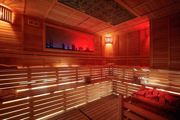 Innenansicht der Sauna im Crystal Sunset Luxury Resort & Spa mit Holzwänden und roter Beleuchtung.