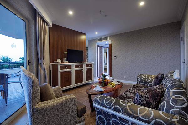 Wohnbereich im Crystal Sunset Luxury Resort & Spa mit Fernseher, Couch und Tisch mit Obst.