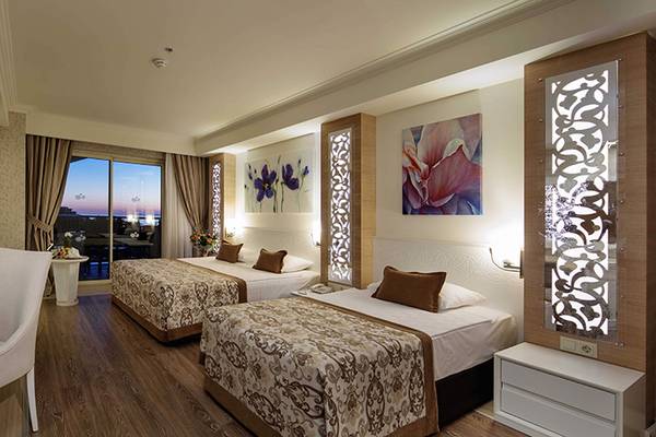 Doppelzimmer im Crystal Sunset Luxury Resort & Spa mit zwei Betten, Schreibtisch und Aussicht auf die Stadt.