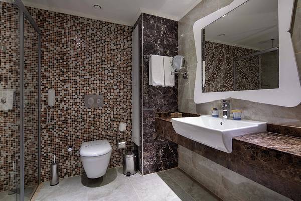 Badezimmer im Crystal Sunset Luxury Resort & Spa mit Marmorwänden, Glasdusche und Waschbecken.