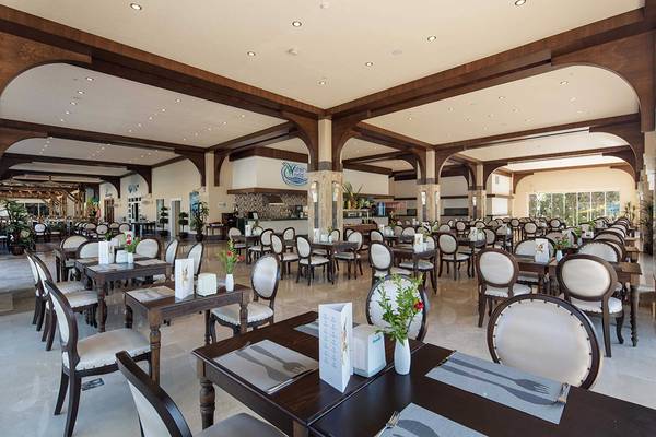 Innenansicht des Restaurants im Crystal Sunset Luxury Resort & Spa mit gedeckten Tischen und dekorativen Blumenarrangements.