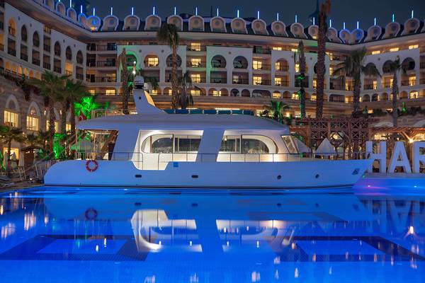 Nachtansicht des Crystal Sunset Luxury Resort & Spa mit einem weißen Boot im Pool