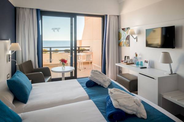 Doppelzimmer mit Meerblick im Grand Teguise Playa Hotel, mit Balkon, Tisch, Stühlen und Blick auf das Meer.