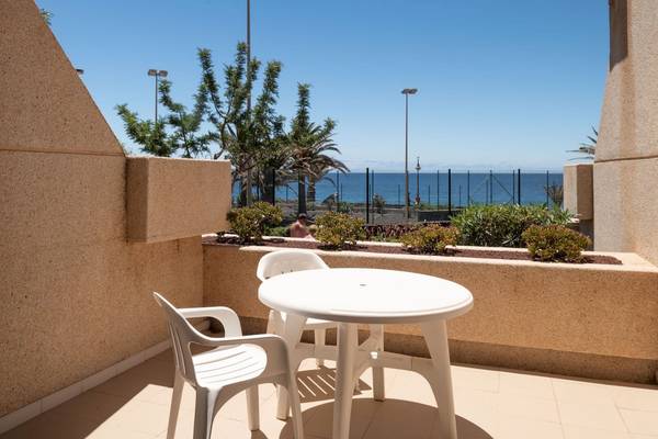 Balkon des Grand Teguise Playa Hotels mit Tisch, Stühlen und Meerblick.