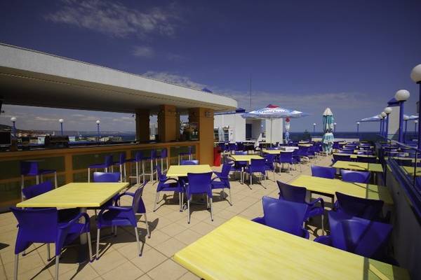 Dachterrasse des Aphrodite Hotel Golden Sands mit gelben Tischen und blauen Stühlen.