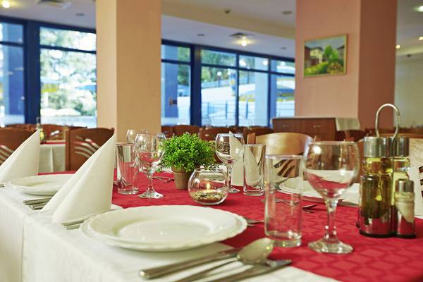 Restauranttisch im Aphrodite Hotel Golden Sands mit Tischdecke, Gläsern und Pflanzen.