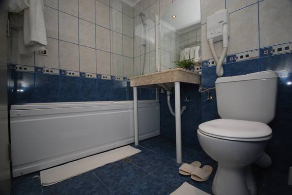 Badezimmer im Aphrodite Hotel Golden Sands mit Badewanne, Toilette und Waschbecken.