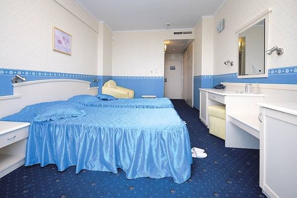 Doppelzimmer im Aphrodite Hotel Golden Sands mit zwei Betten, gelbem Stuhl und weißem Schreibtisch.