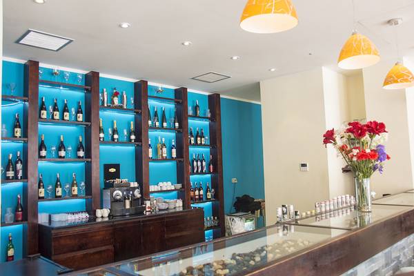 Die Bar des Ancient Sands Golf Resorts mit blauen Regalen und hängenden Lampen.