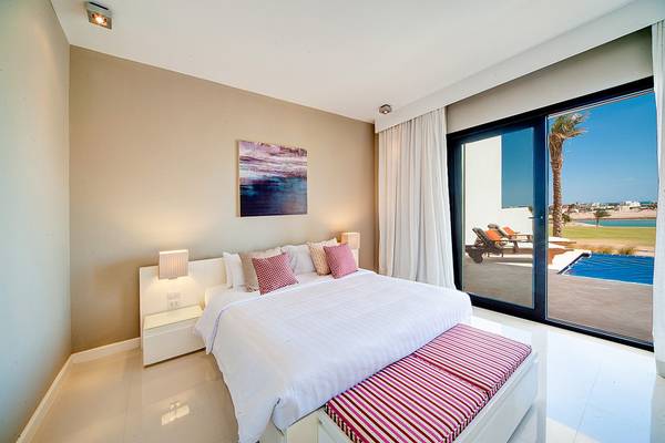 Schlafzimmer mit Doppelbett, Blick auf den Pool und Außenbereich
