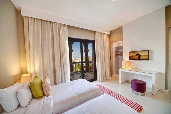 Doppelzimmer im Ancient Sands Golf Resort mit zwei Betten, einem Balkon und modernen Möbeln.