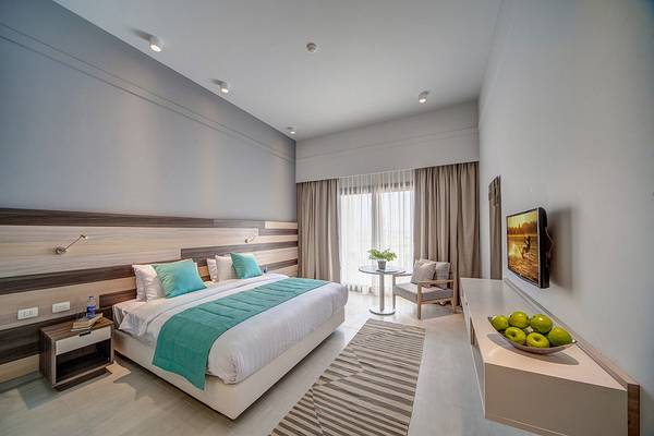 Hotelzimmer im Ancient Sands Golf Resort mit Bett, Tisch, Fernseher und Obstschale.