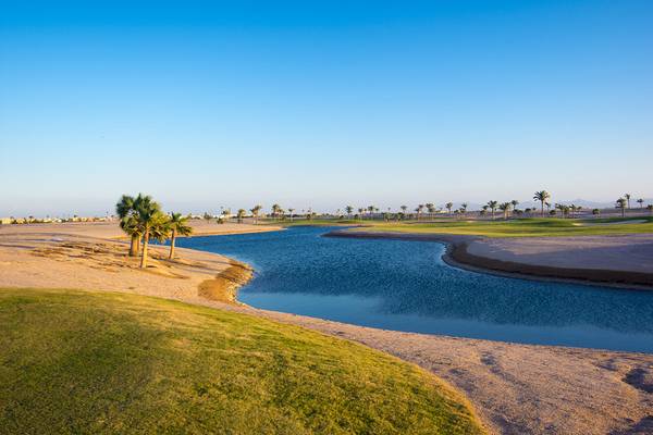 Luftaufnahme des Ancient Sands Golf Resorts mit Wassergraben und Palmen