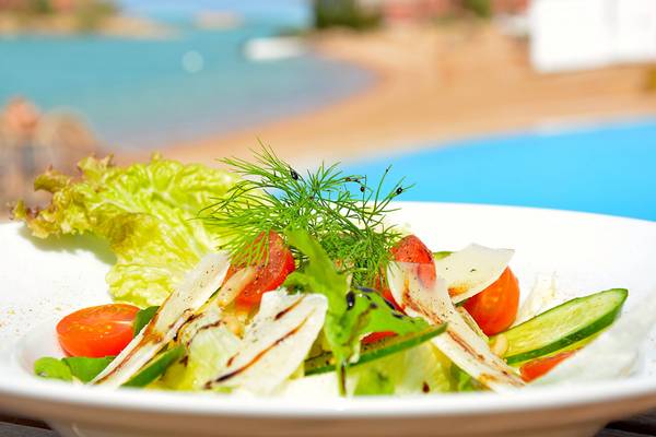 Salat in einem weißen Teller mit einem Pool im Hintergrund
