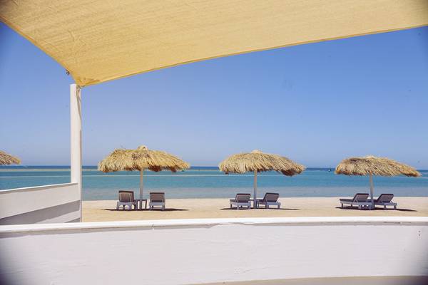 Blick auf den Strand vom Ancient Sands Golf Resort mit Sonnenschirmen und Liegestühlen
