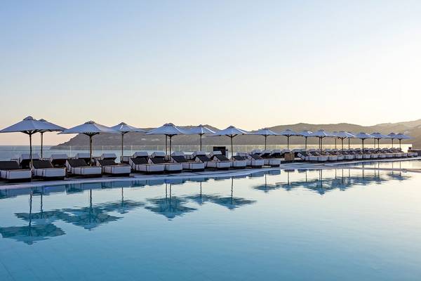 Pool-Loungebereich im Myconian Imperial Hotel mit Sonnenliegen und Sonnenschirmen.