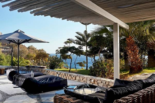 Terrasse des Myconian Imperial Hotels mit Meerblick, schwarze Loungemöbel und ein großer Sonnenschirm.
