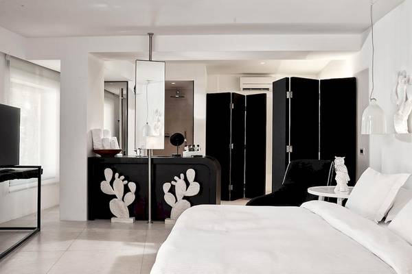 Schlafzimmer im Myconian Imperial Hotel mit modernem weißen Design, schwarzen Akzenten und Kaktus-Dekorationen.