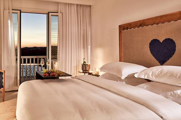Schlafzimmer des Myconian Imperial mit Blick auf den Sonnenuntergang und einem Balkon.