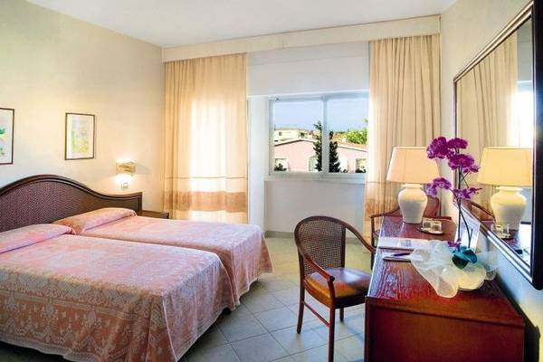 Schlafzimmer im Gabbiano Azzurro Hotel mit zwei Betten, Dekor und Blick aus dem Fenster.