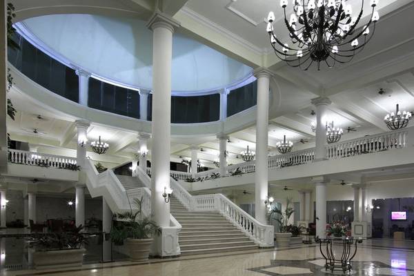Hotellobby des Grand Palladium Jamaica R. & Spa mit Marmorboden, weißen Säulen und hohen Kronleuchtern.