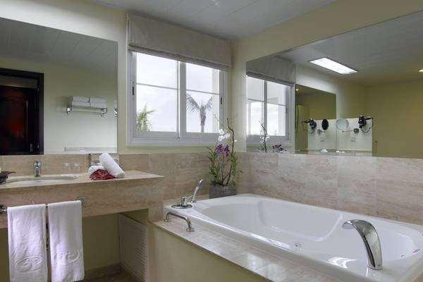 Badezimmer im Grand Palladium Jamaica R. & Spa mit Badewanne, Spiegel und Fenstern.