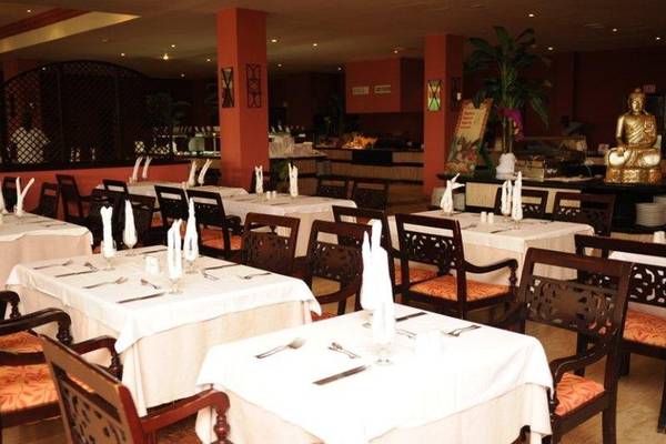 Innenansicht des Restaurants im Grand Palladium Jamaica Resort & Spa mit gedeckten Tischen, Stühlen und einem Buddha-Standbild.